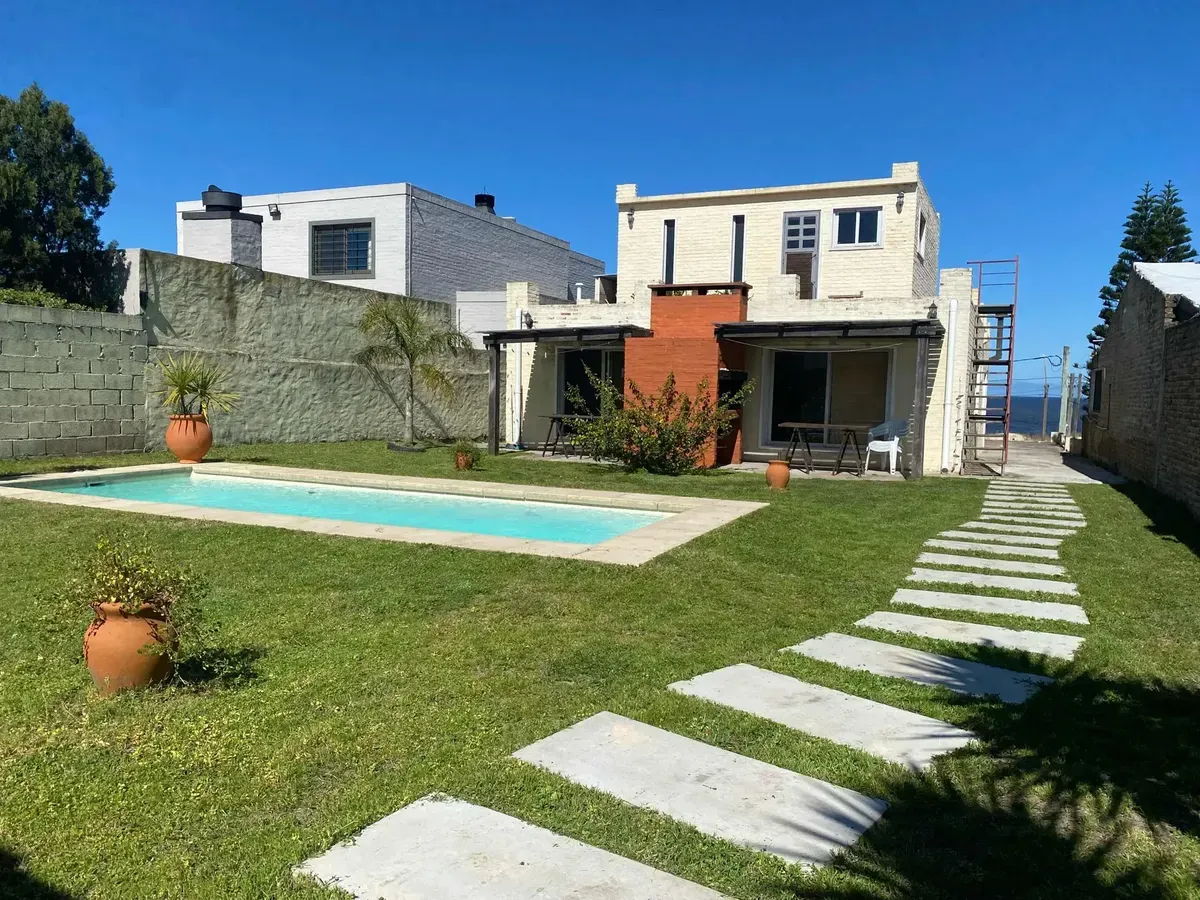 Jardín con piscina, caminito y las casas al fondo