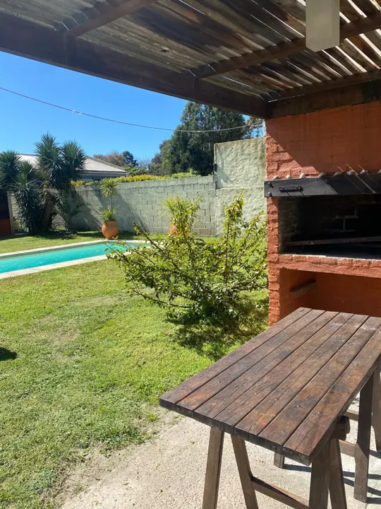 Mesa de madera bajo la pérgola con vista a la piscina